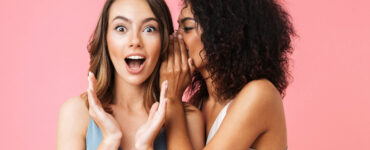 A woman tells a secret to her surprised friend