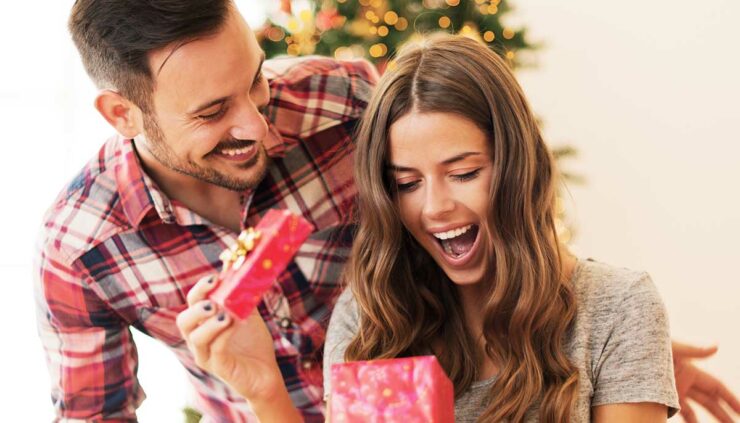 man in plaid gives present to delighted woman