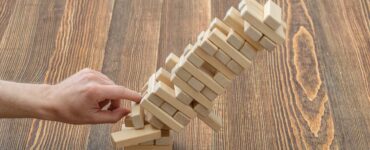 a man pushing a Jenga piece over on a wood table