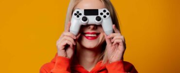 Happy blonde gamer girl holds controller in front of ther face