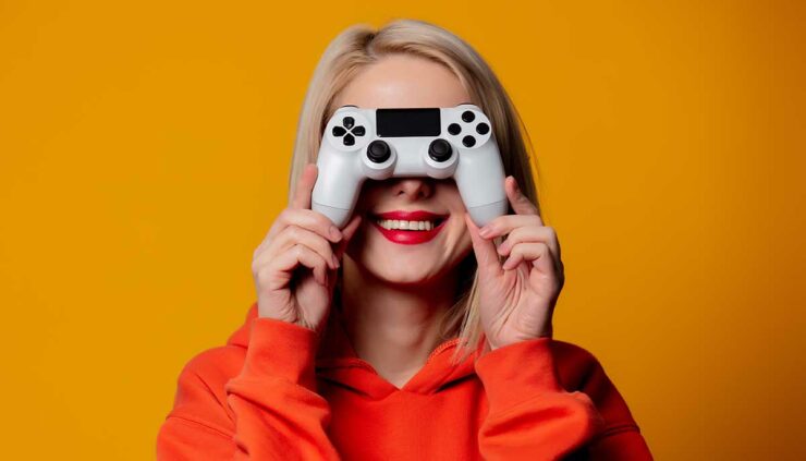 Happy blonde gamer girl holds controller in front of ther face