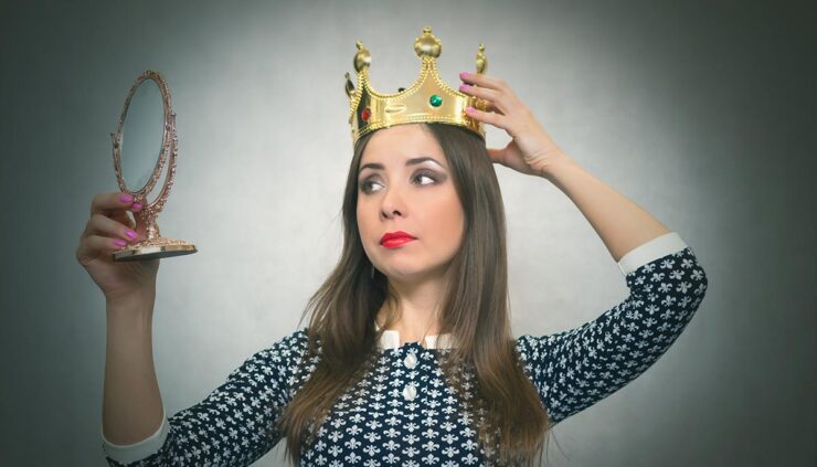 an arrogant woman with a mirror in her hand and a crown on her head