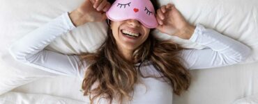 Lazy girl reclining in bed wearing an eye mask