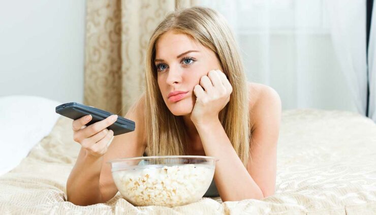 Lazy blonde woman watches TV in bed