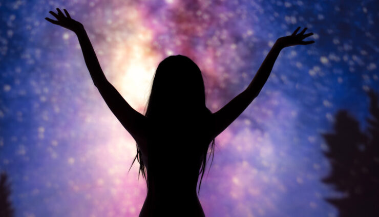 A silhouette of a woman raising her hands in enjoyment before a backdrop of stars.