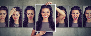 A woman holds up a multiple photos expressing different emotions.