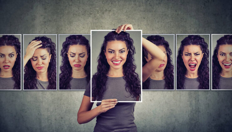 A woman holds up a multiple photos expressing different emotions.