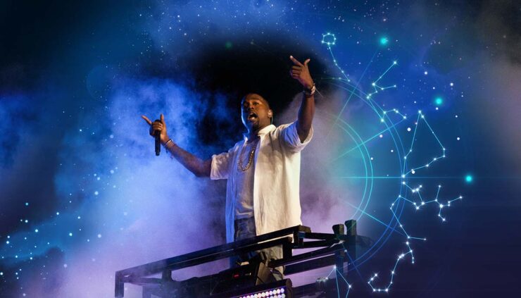 Kanye West floats down a stage surrounded by purple and blue smoke