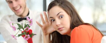 a woman appears disgusted while a guy offers flowers during a blind date