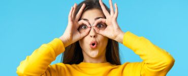 girl in a yellow sweater acting silly with a blue background