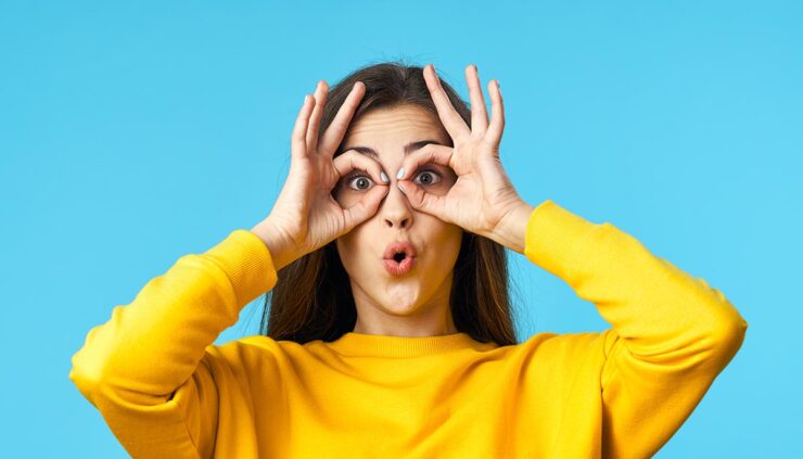 girl in a yellow sweater acting silly with a blue background