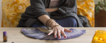 Tarot card reading session Woman`s hand moving over the deck of tarot cards spread over the table