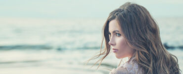 A woman looks dreamily over the ocean.