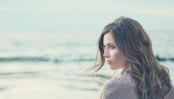 A woman looks dreamily over the ocean.