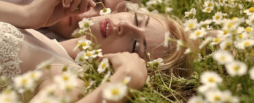 A woman lays in a field of flowers with her lover.