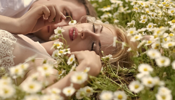 A woman lays in a field of flowers with her lover.