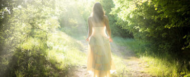 Woman in a white dress walks through the woods