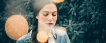 Introspective woman with bokeh orbs around her head.