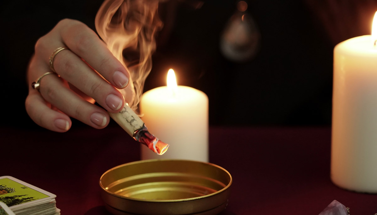 Woman burning paper over candle