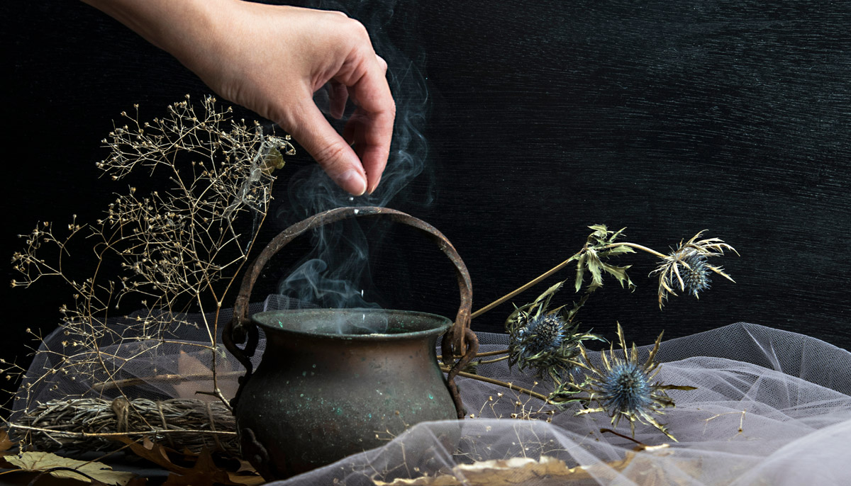 Woman adding herbs to a cauldron