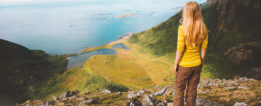 Blond woman on cliff looking at ocean.