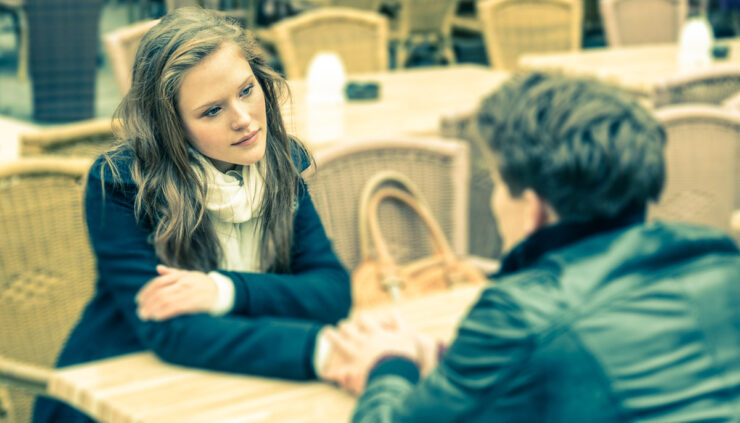 Woman and man hold hands at a cafe