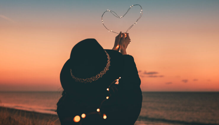 Woman holding heart made of twinkle lights