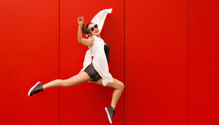 Woman jumping in front of red wall